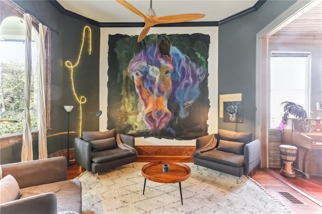 sitting room with visible vents, wood finished floors, a healthy amount of sunlight, and ornamental molding