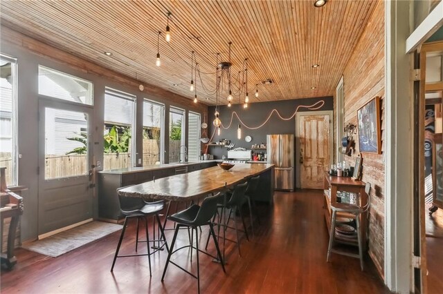 bar with decorative light fixtures, wooden ceiling, freestanding refrigerator, dark wood-style floors, and a sink