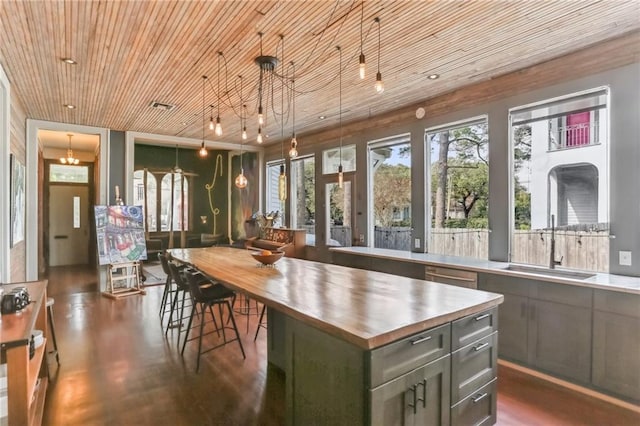 kitchen featuring butcher block countertops, a sink, decorative light fixtures, stainless steel dishwasher, and wooden ceiling