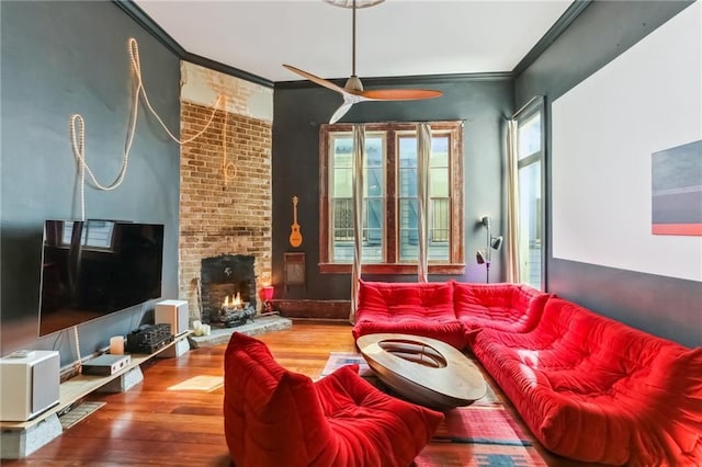 living area with a brick fireplace, wood finished floors, and ornamental molding