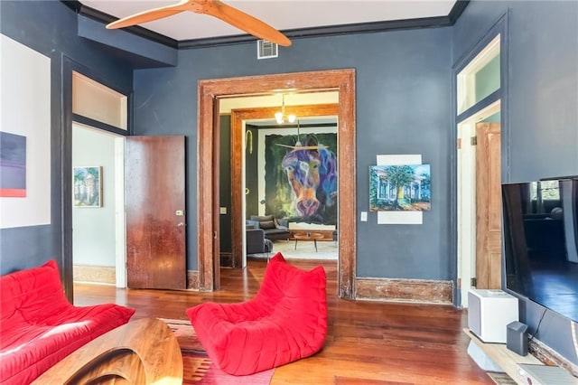 interior space featuring visible vents, crown molding, and wood finished floors