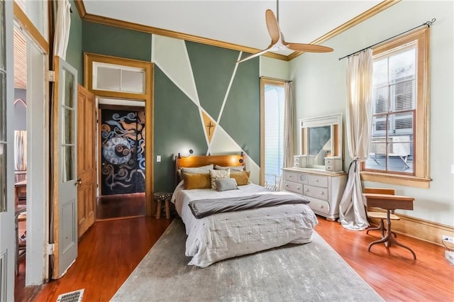 bedroom with visible vents, crown molding, baseboards, and wood finished floors