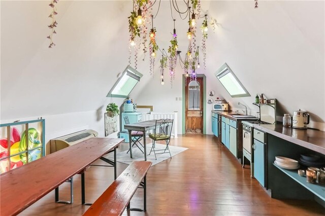 interior space with wood finished floors, white microwave, a sink, dishwasher, and lofted ceiling with skylight