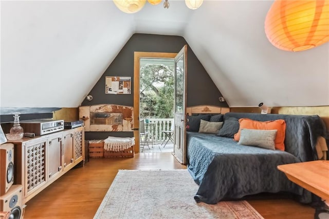 bedroom with wood finished floors, access to exterior, and vaulted ceiling