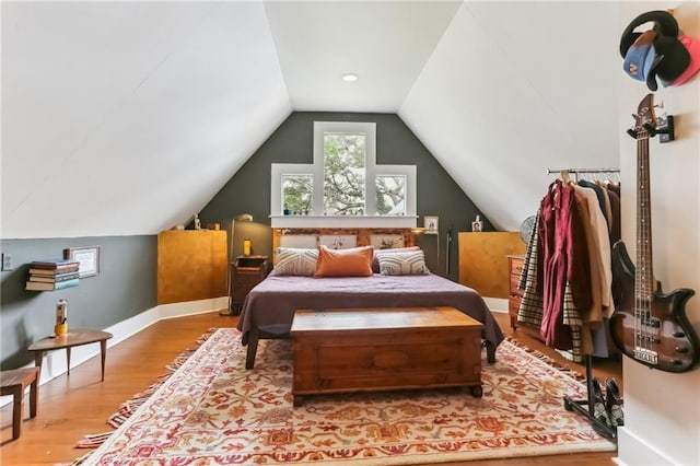 bedroom with vaulted ceiling, baseboards, and wood finished floors