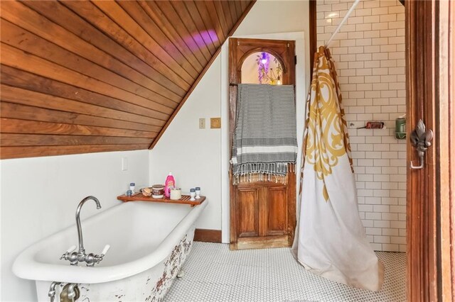 bathroom with baseboards, wood ceiling, vaulted ceiling, tiled shower, and a bath