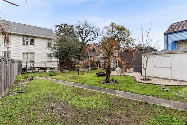 view of yard with an outdoor structure, a shed, a fire pit, and a fenced backyard