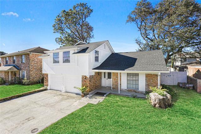 traditional-style house with a front lawn, fence, concrete driveway, a garage, and brick siding