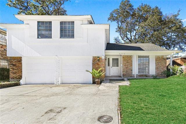 view of front facade featuring driveway, brick siding, and a front yard