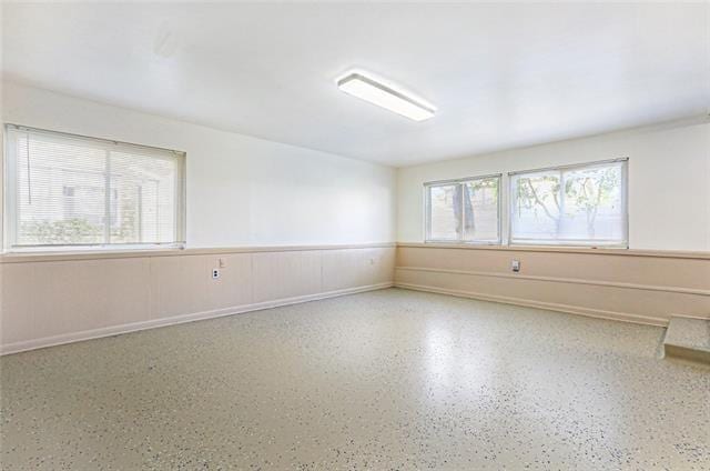 empty room featuring wainscoting and speckled floor