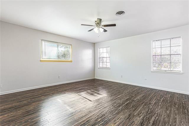 unfurnished room featuring a wealth of natural light, dark wood-style floors, and baseboards