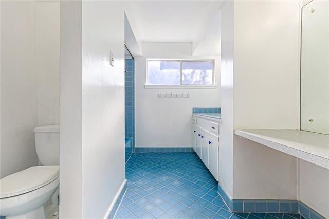 full bath with tile patterned floors, toilet, vanity, and baseboards