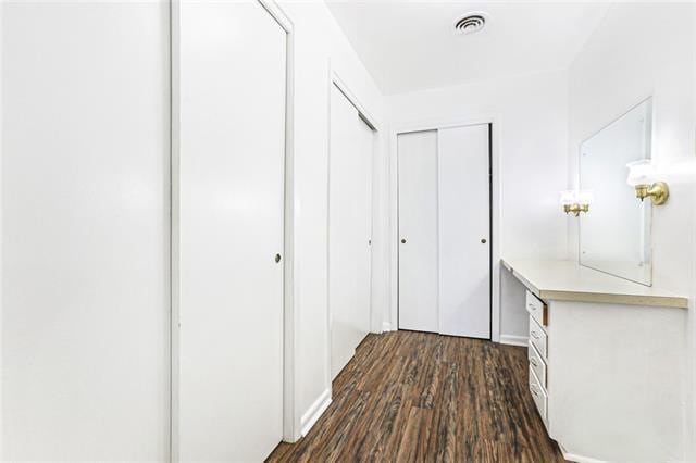 hallway featuring dark wood finished floors and visible vents