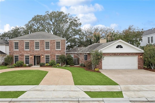 colonial home with a front yard, driveway, a chimney, a garage, and brick siding