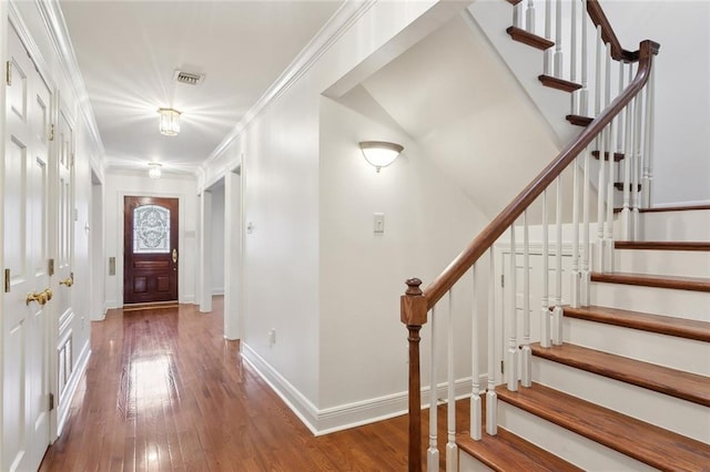 entryway with visible vents, crown molding, baseboards, and hardwood / wood-style floors