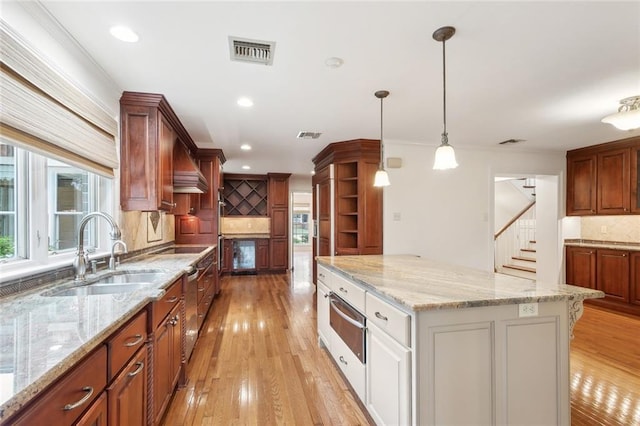 37 Spanish Fort Blvd, New Orleans, LA 70124 - kitchen with visible vents, a kitchen island, light wood-type flooring, a warming drawer, and a sink