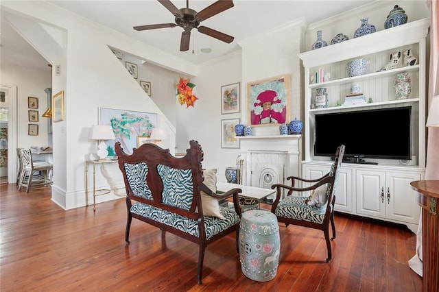 living area with a fireplace, hardwood / wood-style flooring, a ceiling fan, and ornamental molding