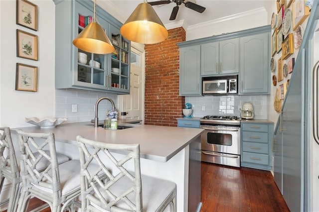 kitchen with glass insert cabinets, crown molding, a peninsula, stainless steel appliances, and a sink