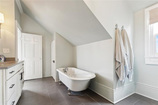 full bathroom with a freestanding tub, lofted ceiling, vanity, and tile patterned flooring