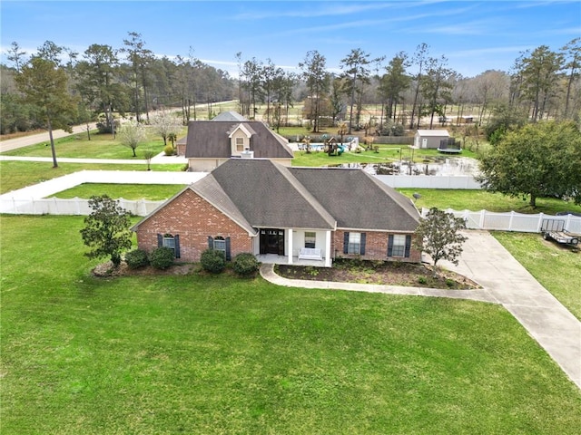 view of front of house featuring brick siding, roof with shingles, a front lawn, and fence