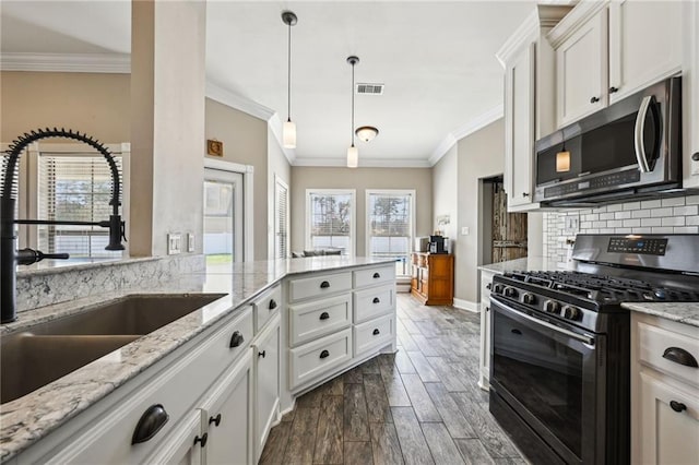 kitchen with tasteful backsplash, visible vents, wood finish floors, appliances with stainless steel finishes, and a sink