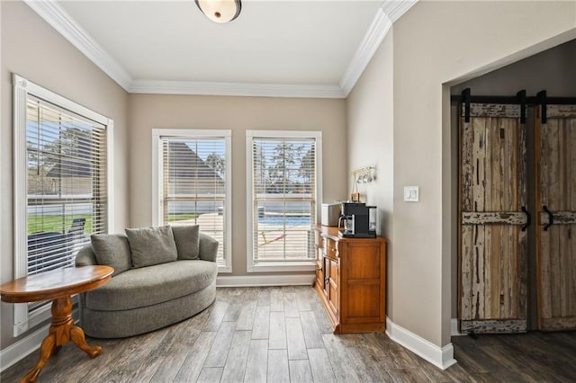 sitting room with a barn door, wood finished floors, and crown molding