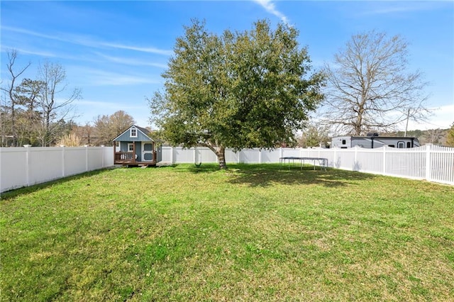 view of yard featuring an outbuilding, a deck, a fenced backyard, and a trampoline