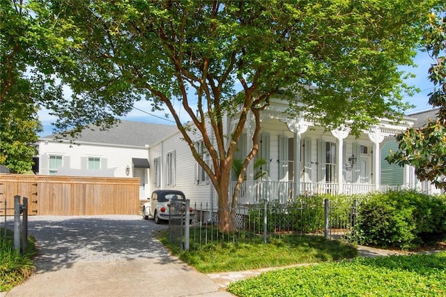 view of front of house featuring a fenced front yard, covered porch, and driveway