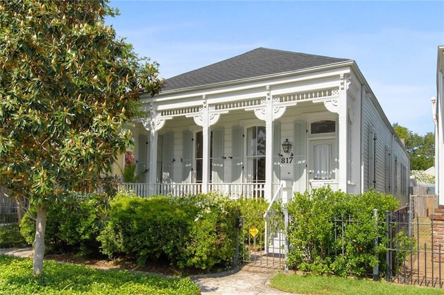 view of front of home with covered porch, roof with shingles, and fence