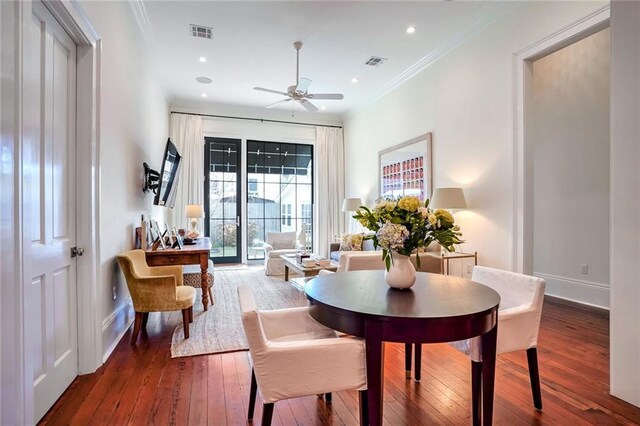 dining area featuring visible vents, baseboards, hardwood / wood-style floors, and crown molding