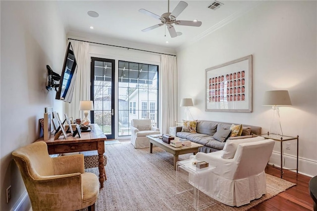 living area with wood finished floors, visible vents, baseboards, ceiling fan, and crown molding