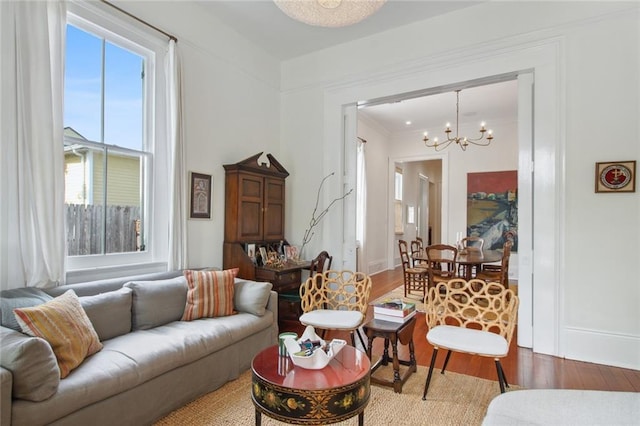 living room with baseboards, an inviting chandelier, wood finished floors, and crown molding