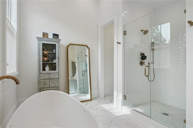 full bathroom featuring a stall shower, marble finish floor, and a freestanding bath