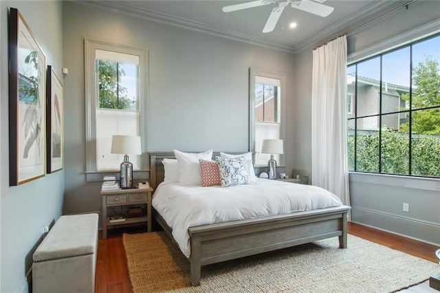 bedroom with baseboards, multiple windows, wood finished floors, and crown molding