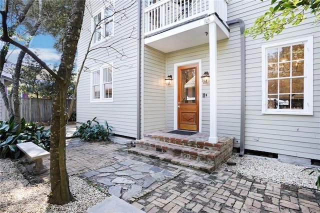 entrance to property featuring a patio area, a balcony, and fence