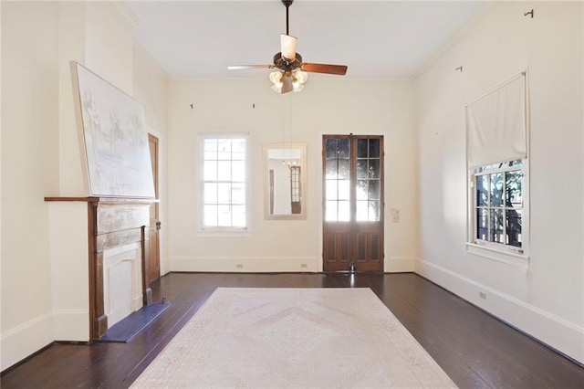 interior space featuring crown molding, wood finished floors, baseboards, and ceiling fan