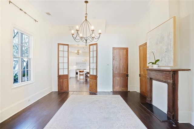 dining area with baseboards, dark wood-type flooring, a notable chandelier, and crown molding