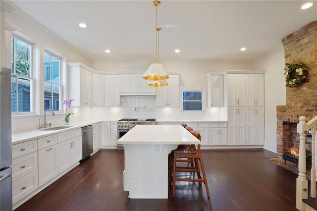 kitchen with dark wood finished floors, backsplash, appliances with stainless steel finishes, and a sink