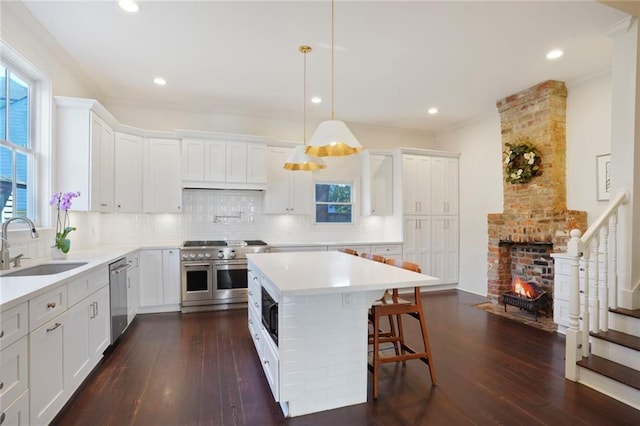 kitchen featuring a sink, dark wood-type flooring, appliances with stainless steel finishes, a kitchen breakfast bar, and backsplash