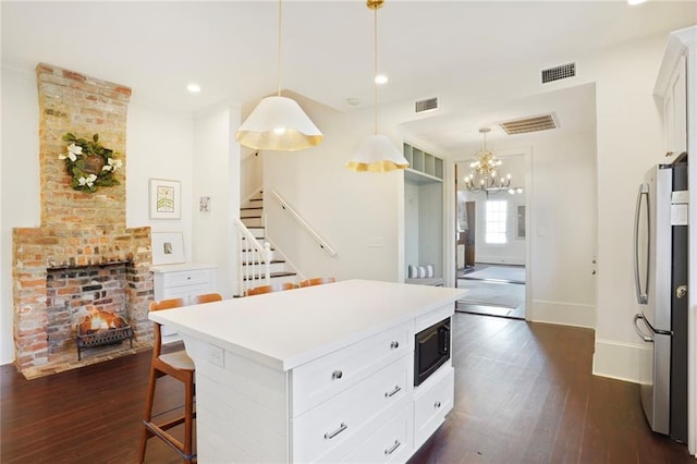 kitchen featuring visible vents, a brick fireplace, freestanding refrigerator, and black microwave