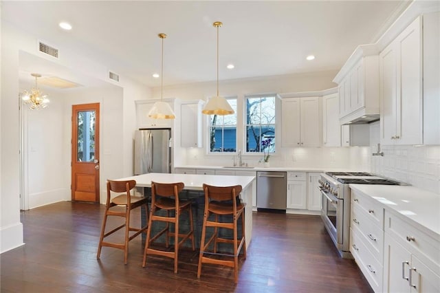 kitchen featuring a kitchen bar, visible vents, a sink, stainless steel appliances, and decorative backsplash