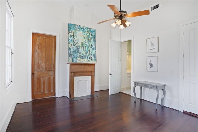 interior space with visible vents, wood finished floors, crown molding, baseboards, and ceiling fan