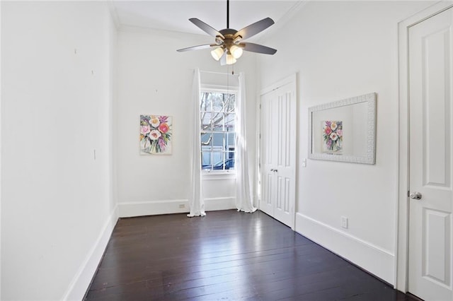 interior space with baseboards, dark wood finished floors, a ceiling fan, and crown molding