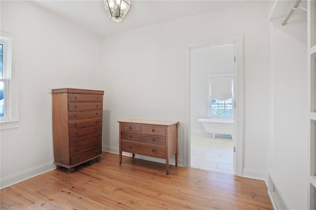 interior space featuring light wood-type flooring, baseboards, and connected bathroom