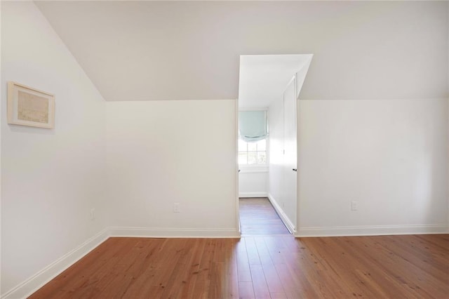 bonus room with hardwood / wood-style floors, vaulted ceiling, and baseboards