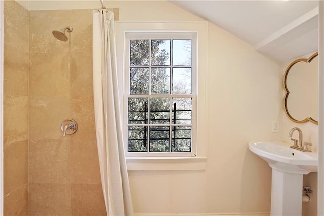 bathroom with a wealth of natural light, tiled shower, and vaulted ceiling