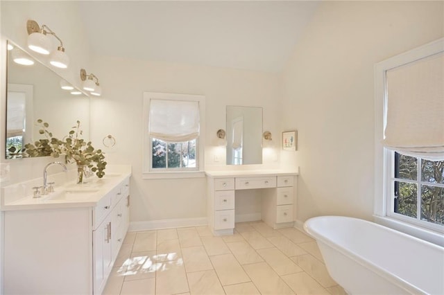 bathroom with tile patterned floors, baseboards, a freestanding bath, vanity, and vaulted ceiling