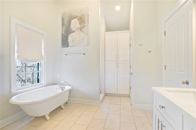 bathroom with tile patterned flooring, vanity, baseboards, and a freestanding tub