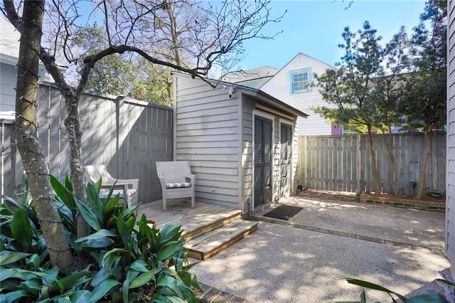 view of patio / terrace featuring an outdoor structure, a fenced backyard, and a wooden deck