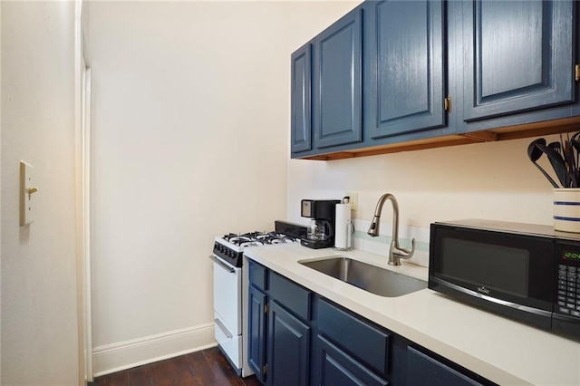 kitchen with white range with gas stovetop, a sink, light countertops, black microwave, and blue cabinets